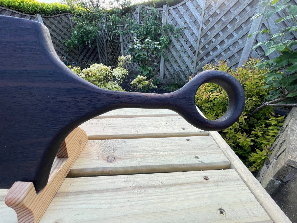 Close-up of the rounded cut-out handle on a handmade dark oak charcuterie board with a hand-torched finished. 