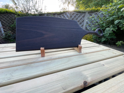 Full view of a handmade dark oak charcuterie serving board with a circular handle and hand-torched finish. 