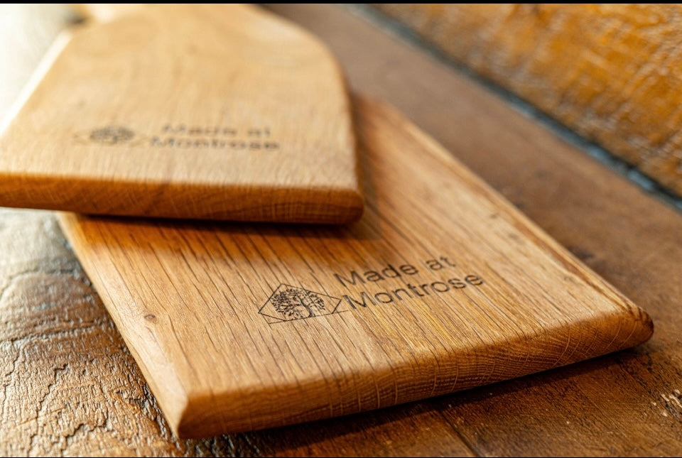 Close-up of handcrafted wooden serving boards showing natural hardwood grain and engraved Made at Montrose branding, handmade in Lancashire.