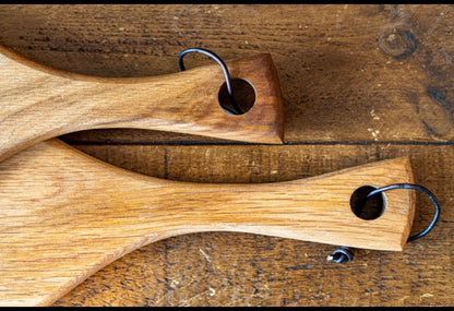 Close-up of two handmade wooden serving boards with curved handles and rustic hanging loops, crafted from natural hardwood by Made at Montrose in Lancashire.