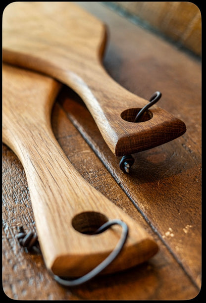 Close-up of handcrafted wooden serving board handles with rustic hanging loops and natural hardwood grain, handmade by Made at Montrose in Lancashire.
