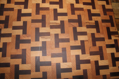 Close-up of a handmade end grain chopping board showing the geometric T-shape pattern in contrasting beech and sapele hardwoods. 