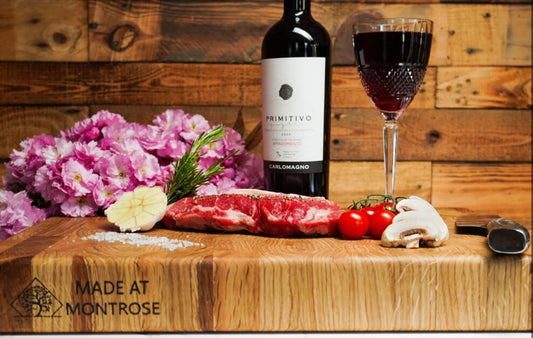 Montrose Edition solid oak end grain chopping board with Made at Montrose engraving, styled with food, flowers and red wine  